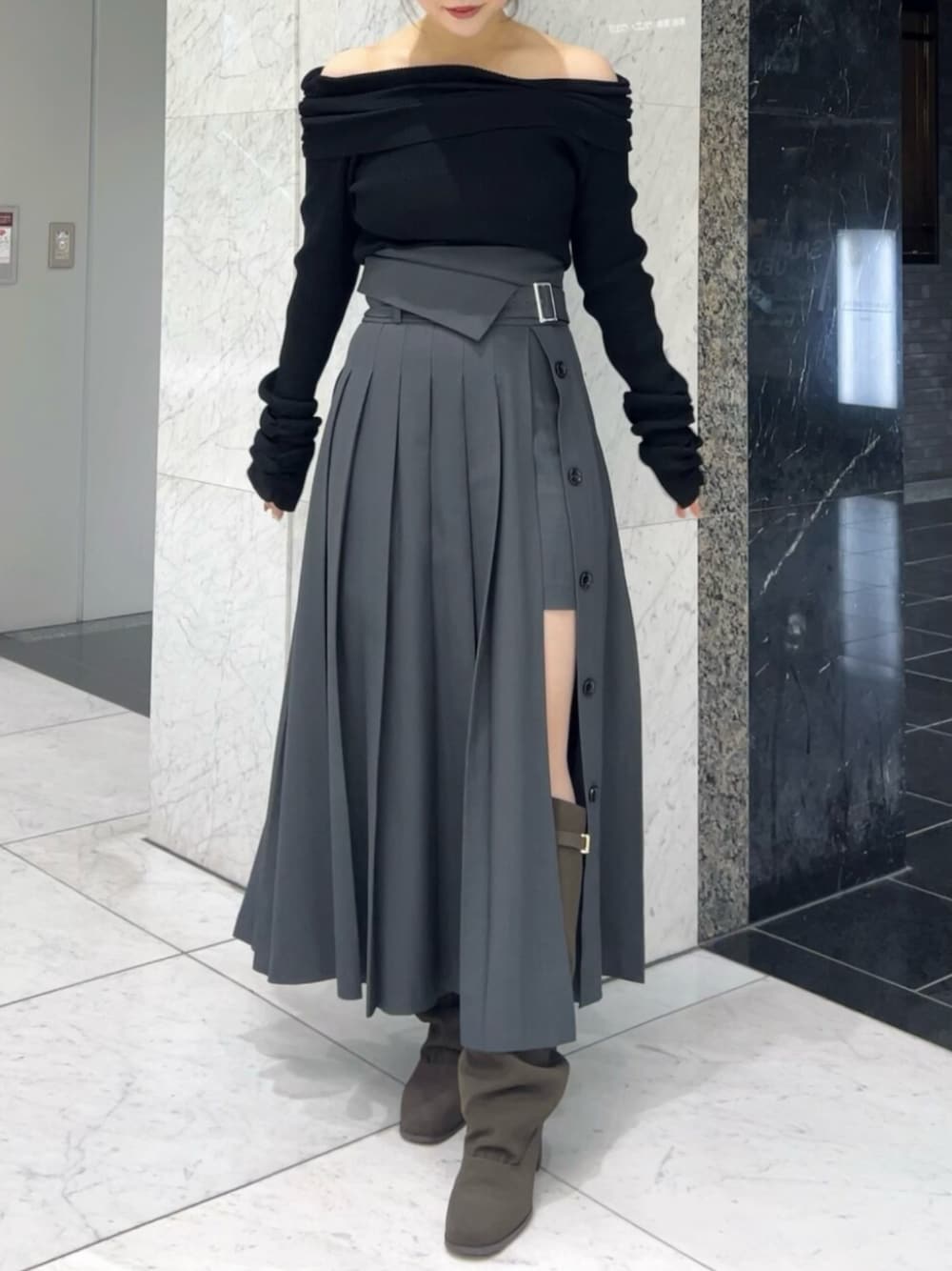 ブラック系のニット/セーター、グレー系のスカート、ブラウン系のブーツを着用したレディースの秋コーディネートの1枚目の写真