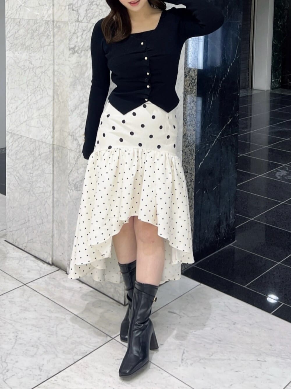 ブラック系のブーツ、ブラック系のニット/セーター、ホワイト系のスカートを着用したレディースの春コーディネートの1枚目の写真