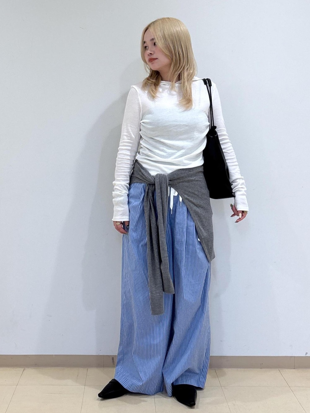 グレー系のニット/セーター、ブラック系のサンダル、ブラック系のショルダーバッグを着用したレディースの秋コーディネートの1枚目の写真