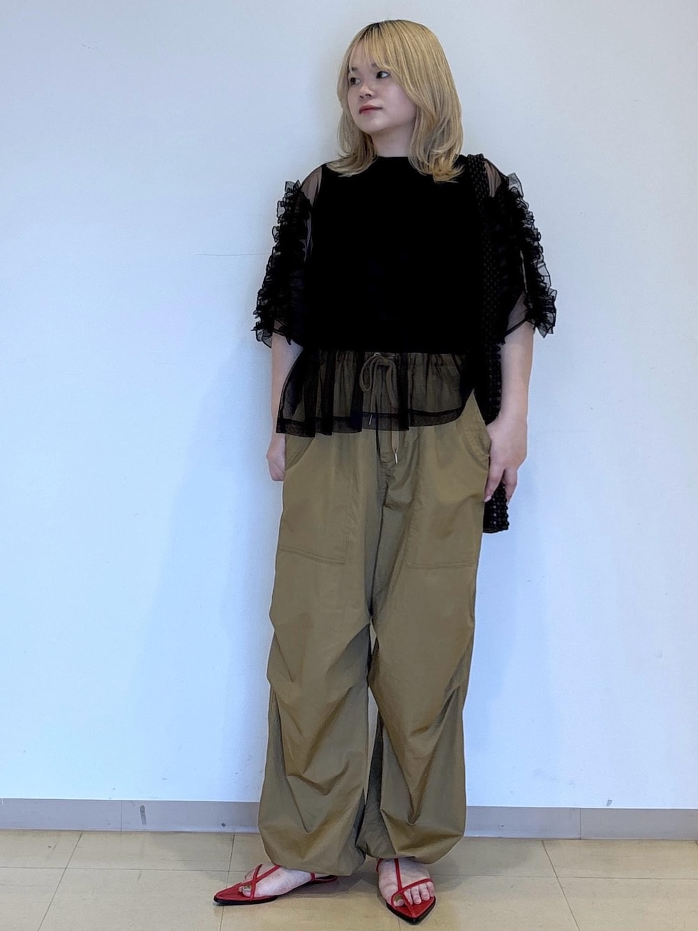レッド系のサンダル、ブラック系のTシャツ/カットソー、レッド系のショルダーバッグを着用したレディースの春コーディネートの1枚目の写真