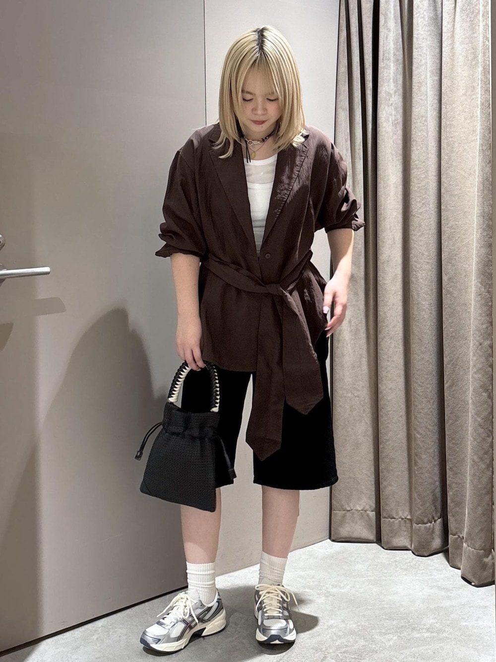 ブラック系のショルダーバッグ、ブラック系のデニムパンツ、ブラウン系のテーラードジャケットを着用したレディースの春コーディネートの1枚目の写真
