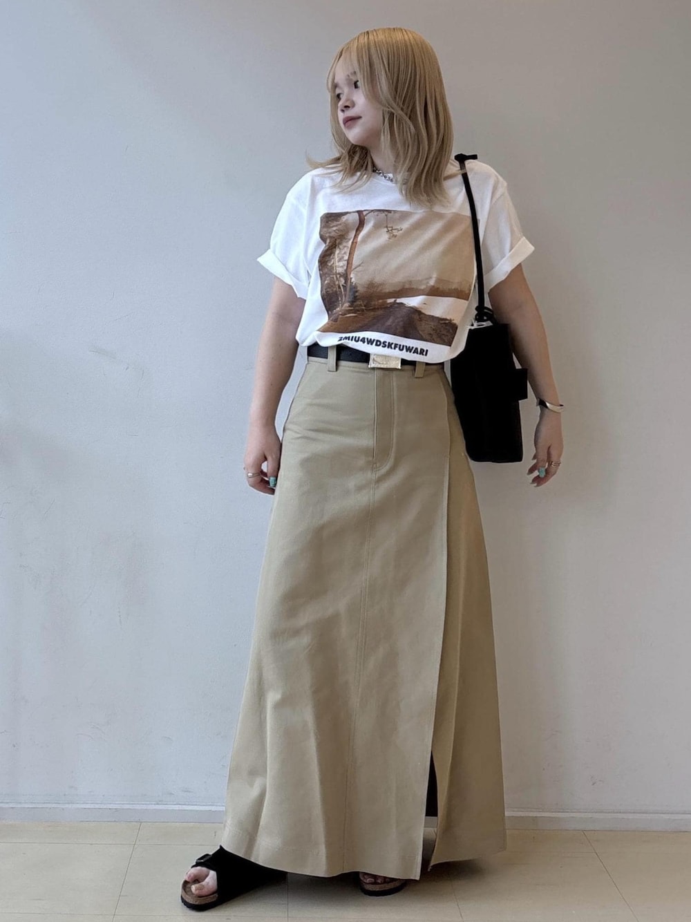 ホワイト系のTシャツ/カットソー、ベージュ系のスカート、ブラック系のショルダーバッグを着用したレディースの夏コーディネートの1枚目の写真