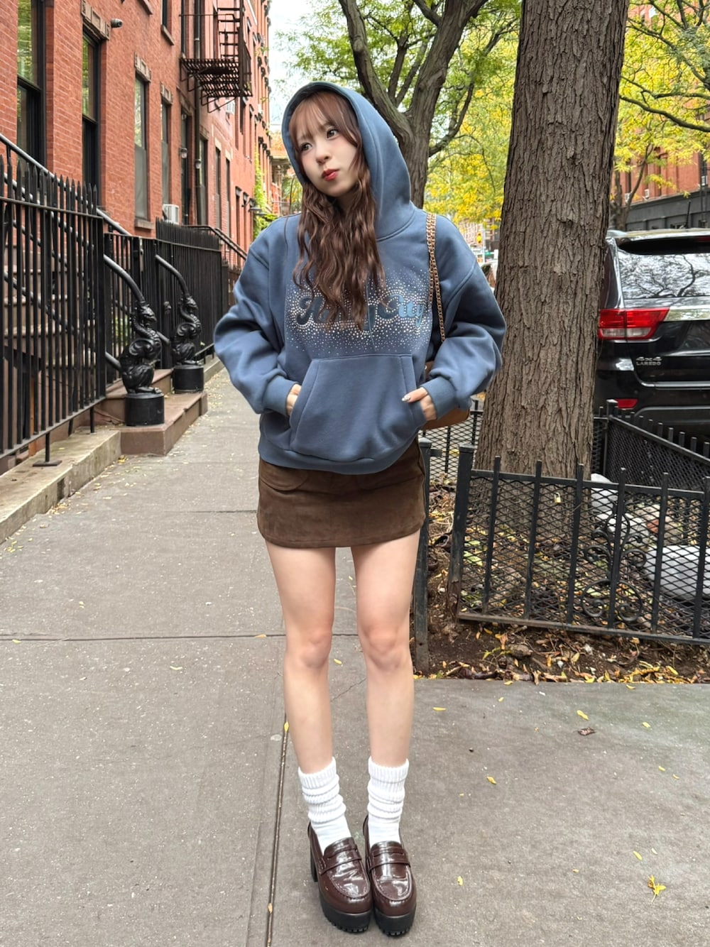 ブルー系のパーカー、ブラウン系のボストンバッグ、ブラウン系のスカートを着用したレディースの冬コーディネートの1枚目の写真