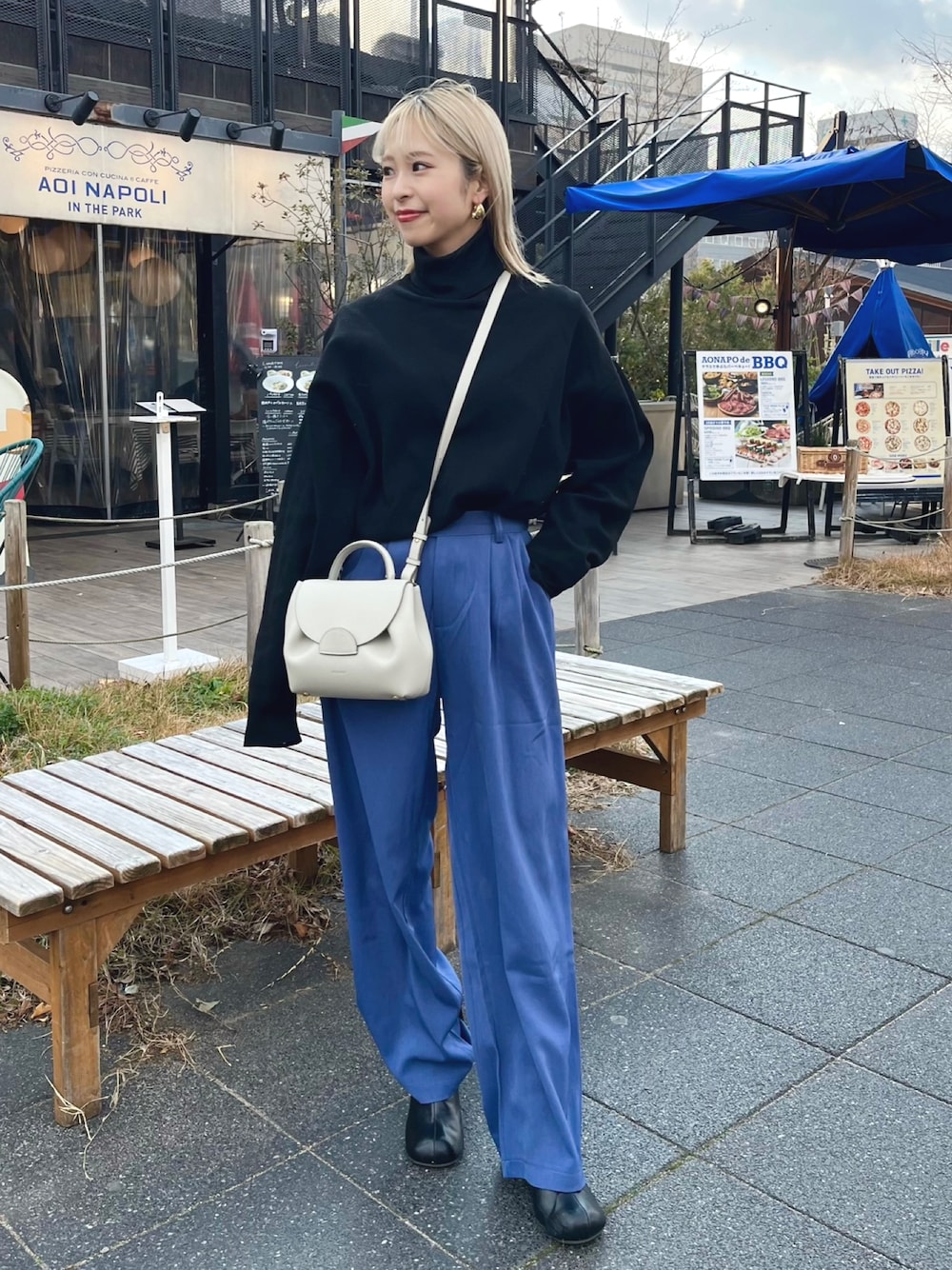 ブラック系のニット/セーター、ホワイト系のバッグ、ブルー系のパンツを着用したレディースの冬コーディネートの1枚目の写真