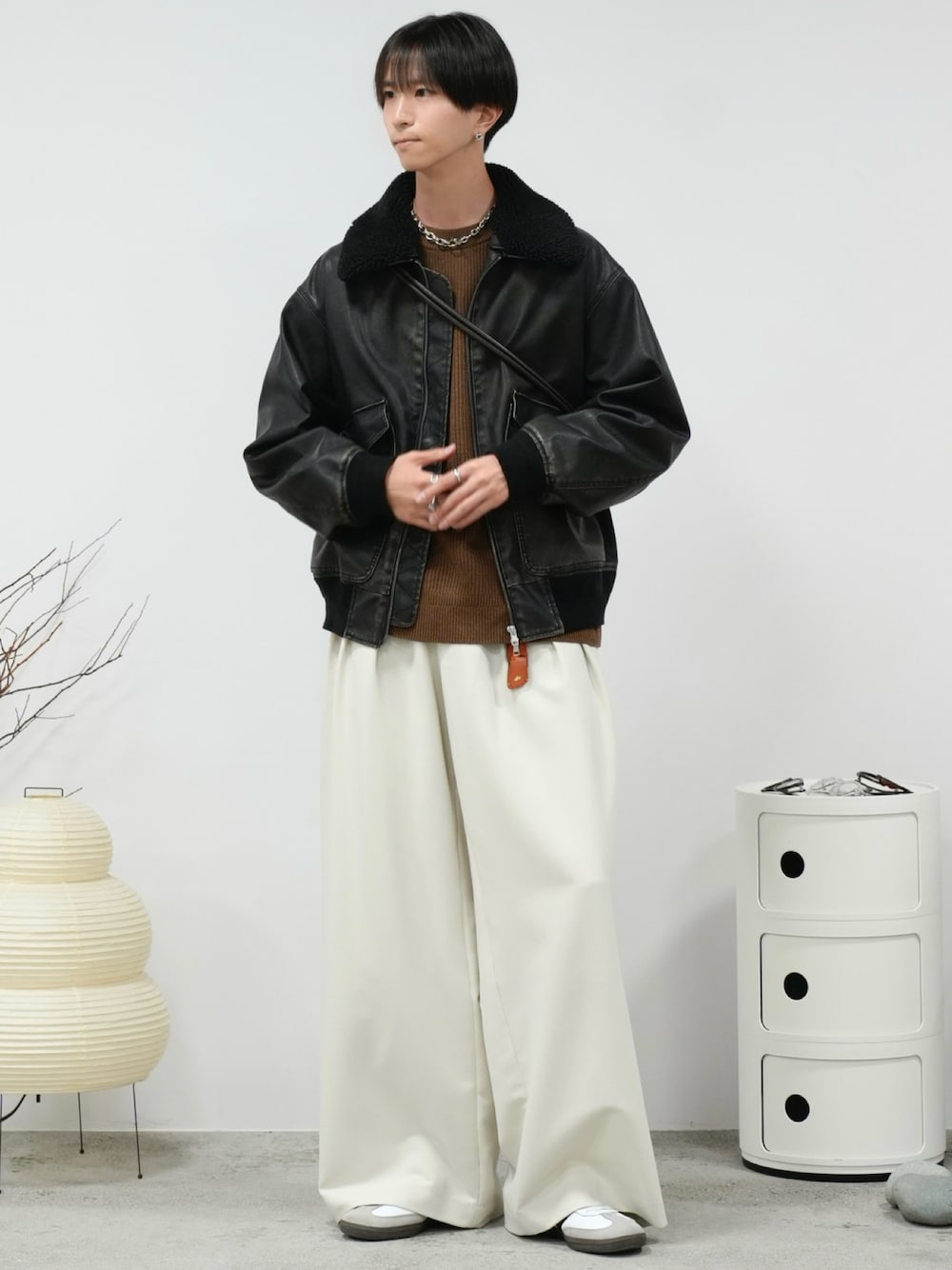 イエロー系のニット/セーター、ブラック系のブルゾン、ホワイト系のスラックスを着用したメンズの冬コーディネートの1枚目の写真