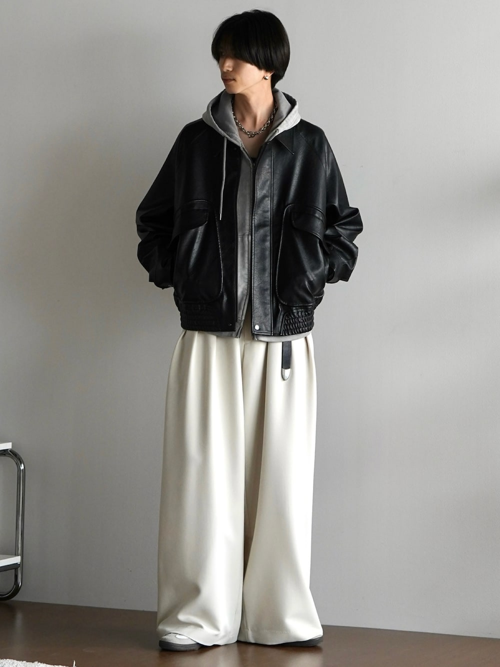 グレー系のパーカー、ブラック系のブルゾン、ホワイト系のスラックスを着用したメンズの秋コーディネートの1枚目の写真