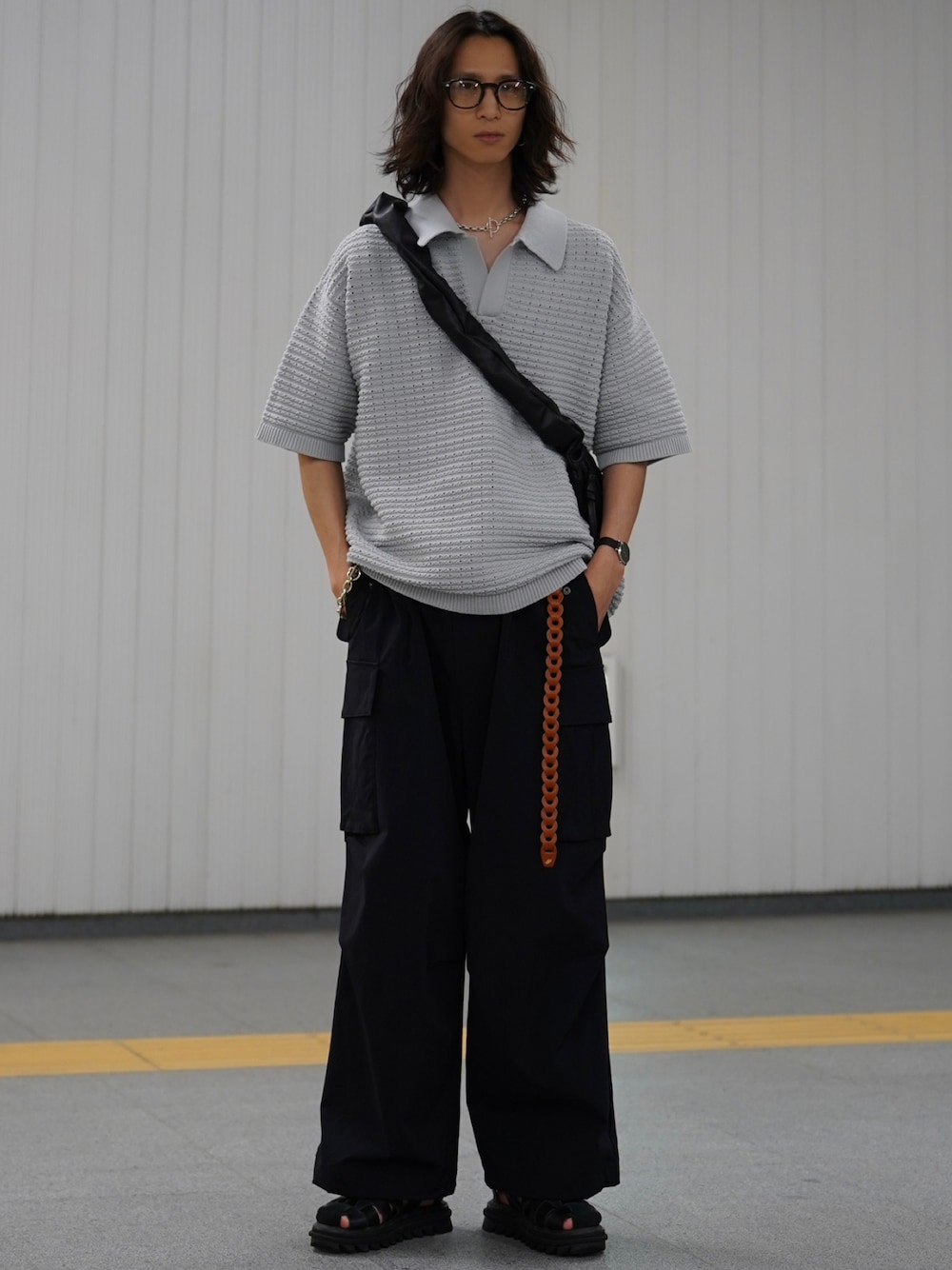 グレー系のポロシャツ、ブラック系のカーゴパンツ、ブラック系のサンダルを着用したメンズの冬コーディネートの1枚目の写真