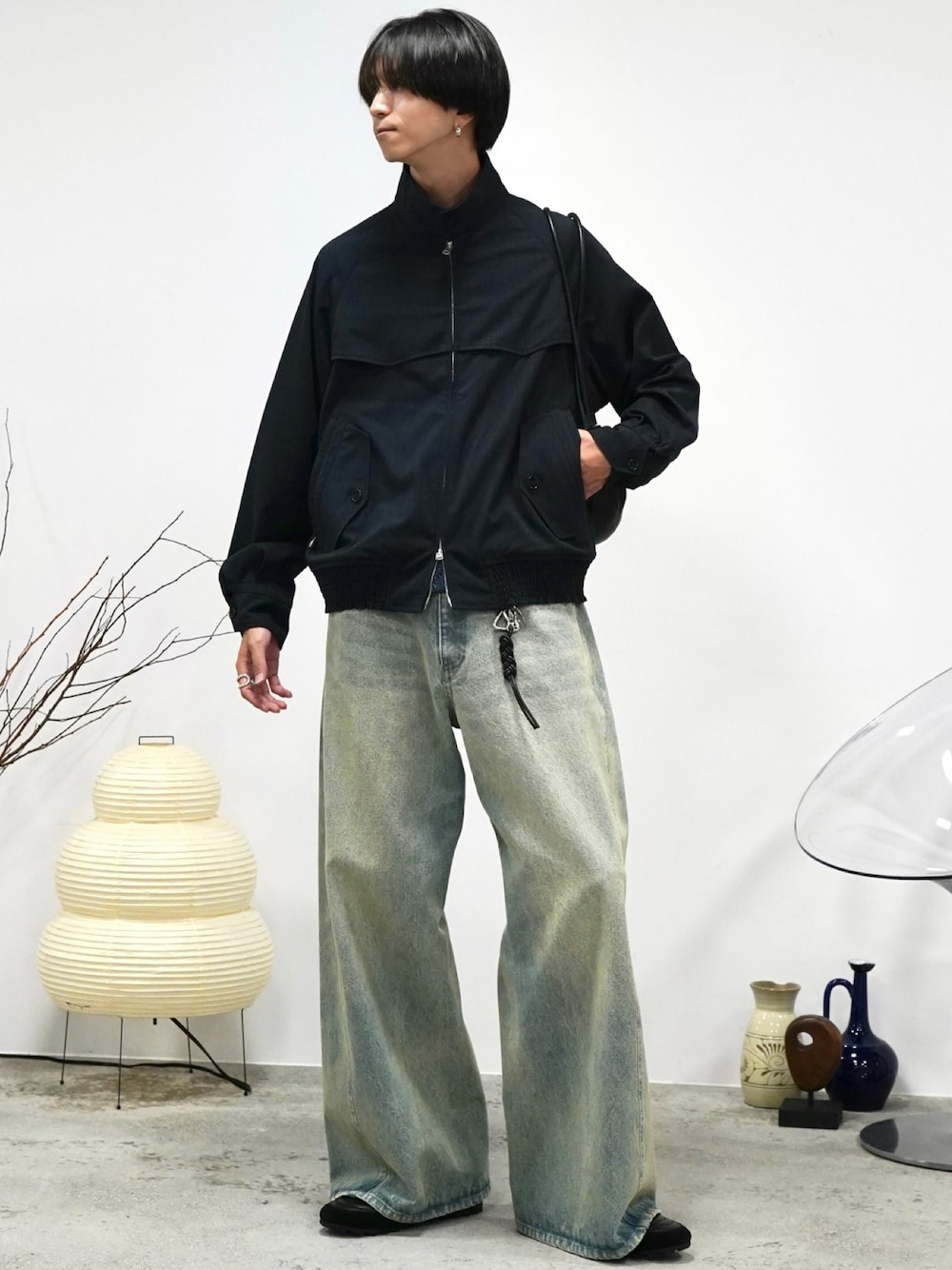 グレー系のブルゾン、ブルー系のデニムパンツ、ブラック系のショルダーバッグを着用したメンズの秋コーディネートの1枚目の写真