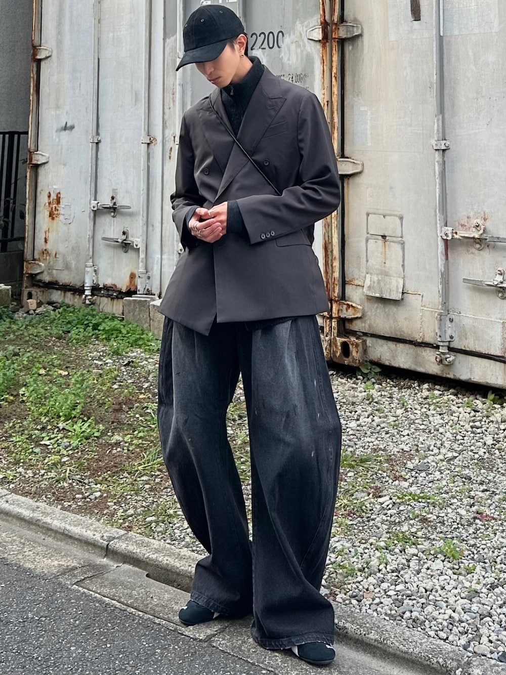 ブラック系のデニムパンツ、ブラック系のスニーカー、ブラック系のベストを着用したメンズの秋コーディネートの1枚目の写真