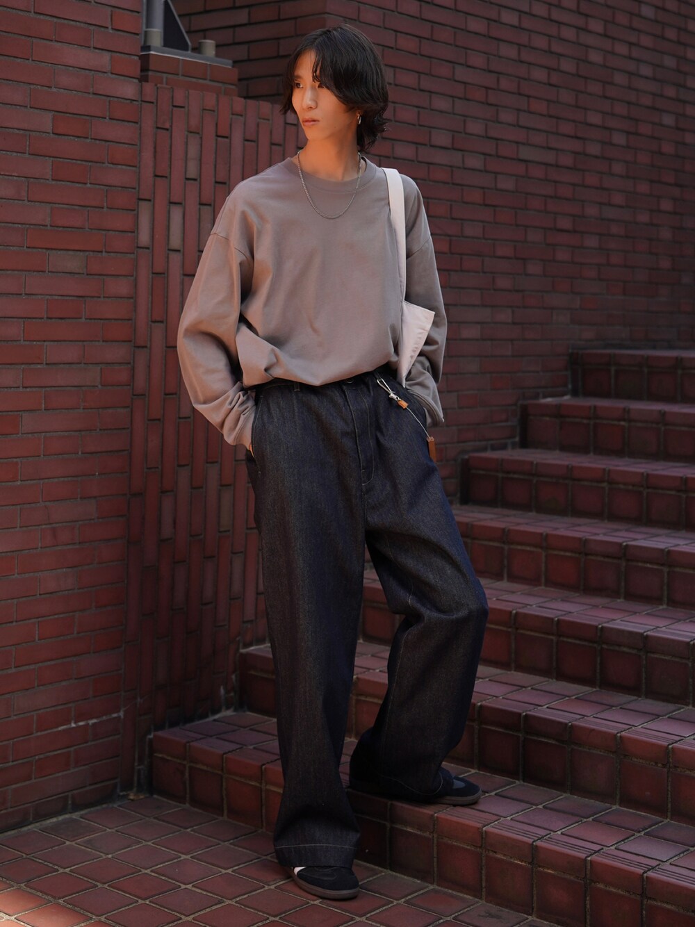 グレー系のTシャツ/カットソー、ブルー系のデニムパンツ、ブラック系のスニーカーを着用したメンズの夏コーディネートの1枚目の写真