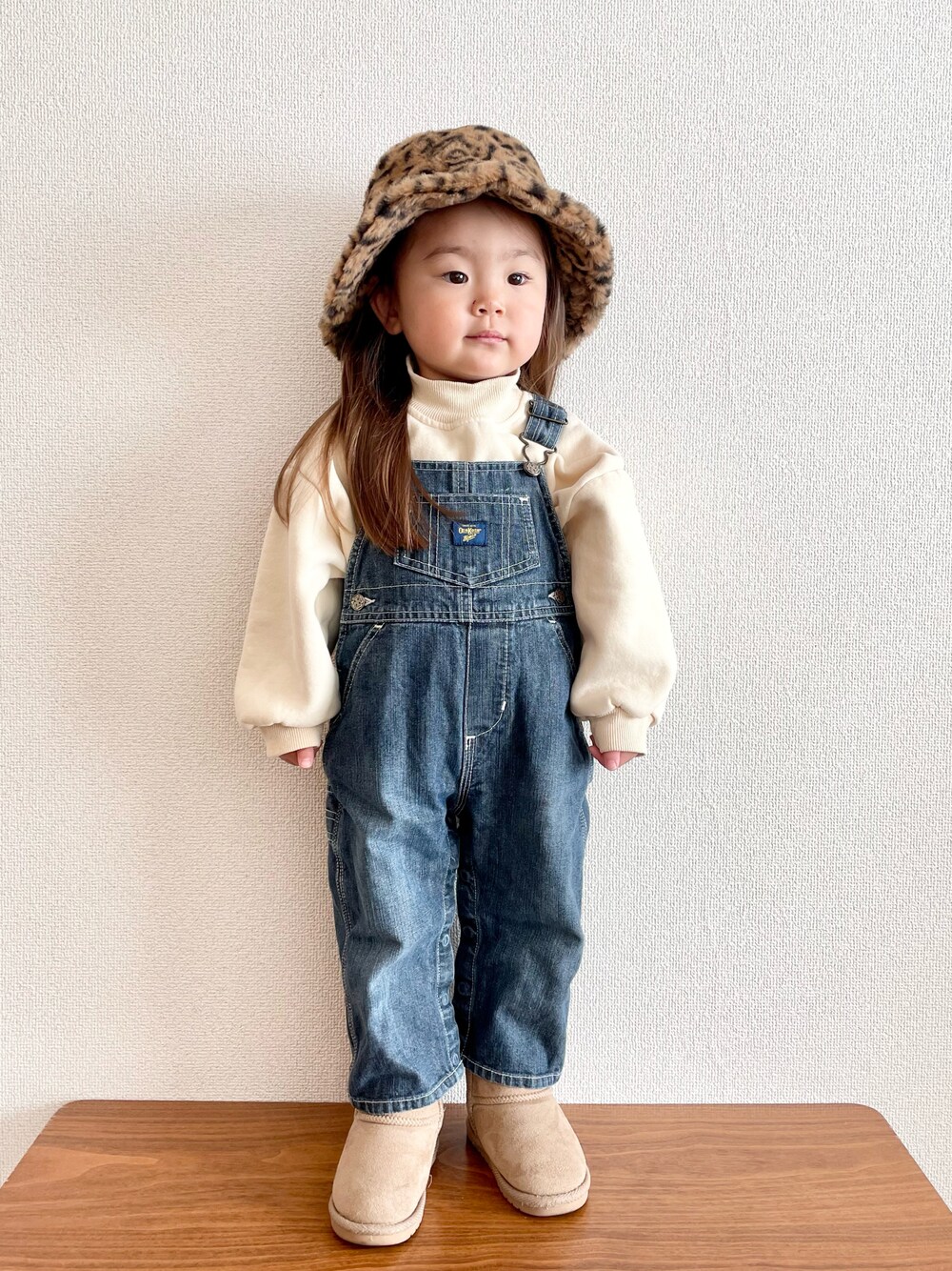 ブルー系のサロペット/オーバーオール、ベージュ系のブーツ、ベージュ系のキャップを着用したキッズの冬コーディネートの1枚目の写真