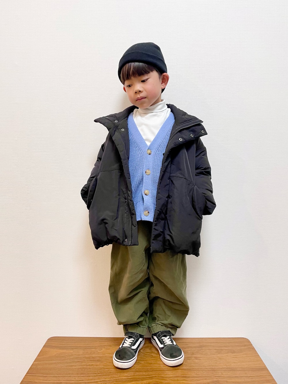 ブルー系のカーディガン/ボレロ、ブラック系のダウンジャケット/コート、グリーン系のカーゴパンツを着用したキッズの冬コーディネートの1枚目の写真