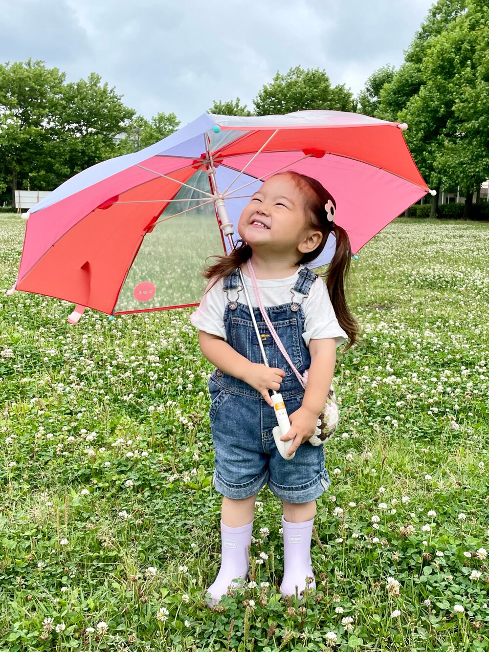 ブルー系のサロペット/オーバーオール、パープル系のレインシューズ、ピンク系のショルダーバッグを着用したキッズの夏コーディネートの1枚目の写真