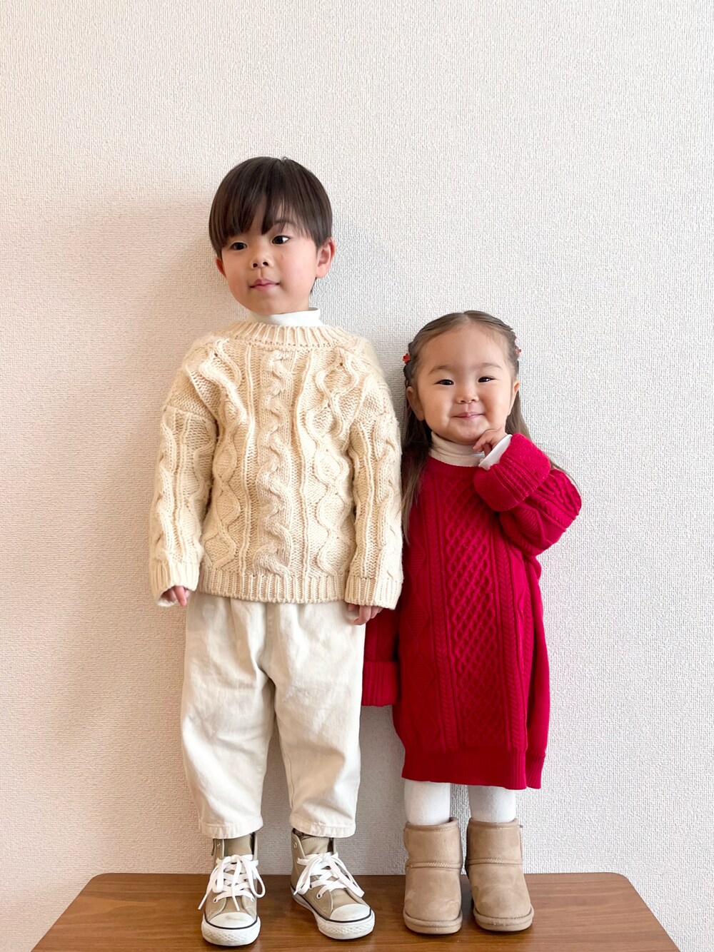 レッド系のニット/セーター、ベージュ系のブーツ、ベージュ系のカーディガン/ボレロを着用したキッズの冬コーディネートの1枚目の写真