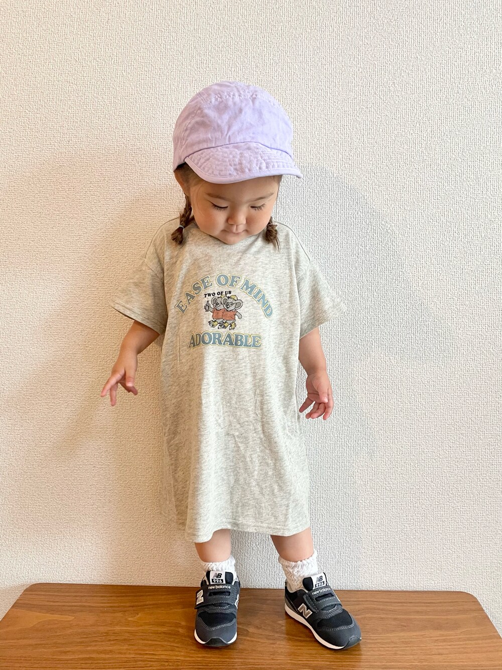 ホワイト系のワンピース、ブルー系のスニーカー、パープル系のキャップを着用したキッズの春コーディネートの1枚目の写真