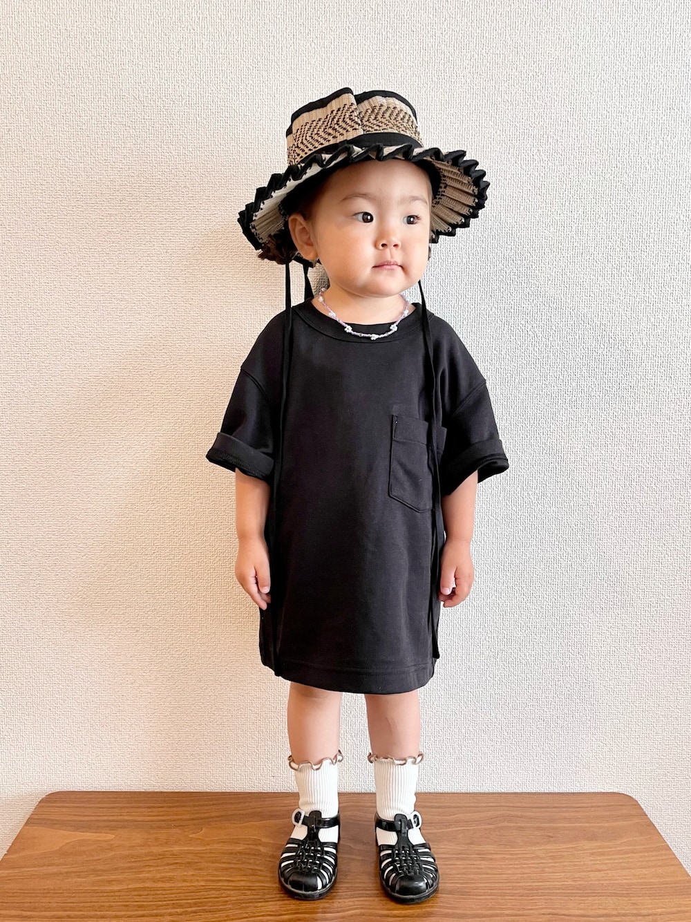 ブラック系のTシャツ/カットソー、ブラック系のサンダル、ブラック系のハットを着用したキッズの夏コーディネートの1枚目の写真