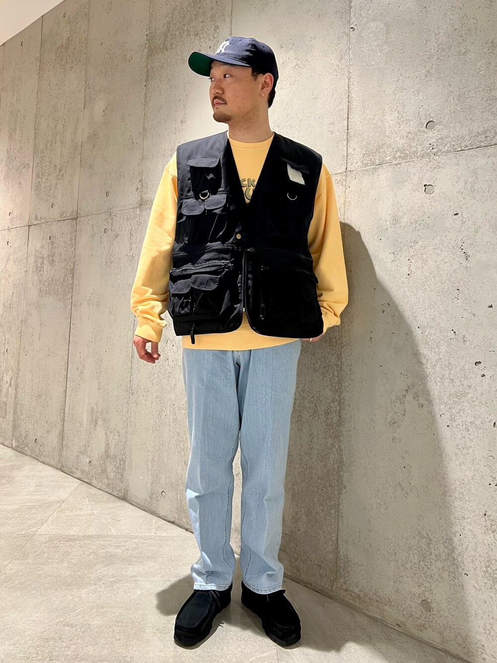 ブラック系のベスト、ブルー系のデニムパンツ、ブラック系のブーツを着用したメンズの春コーディネートの1枚目の写真