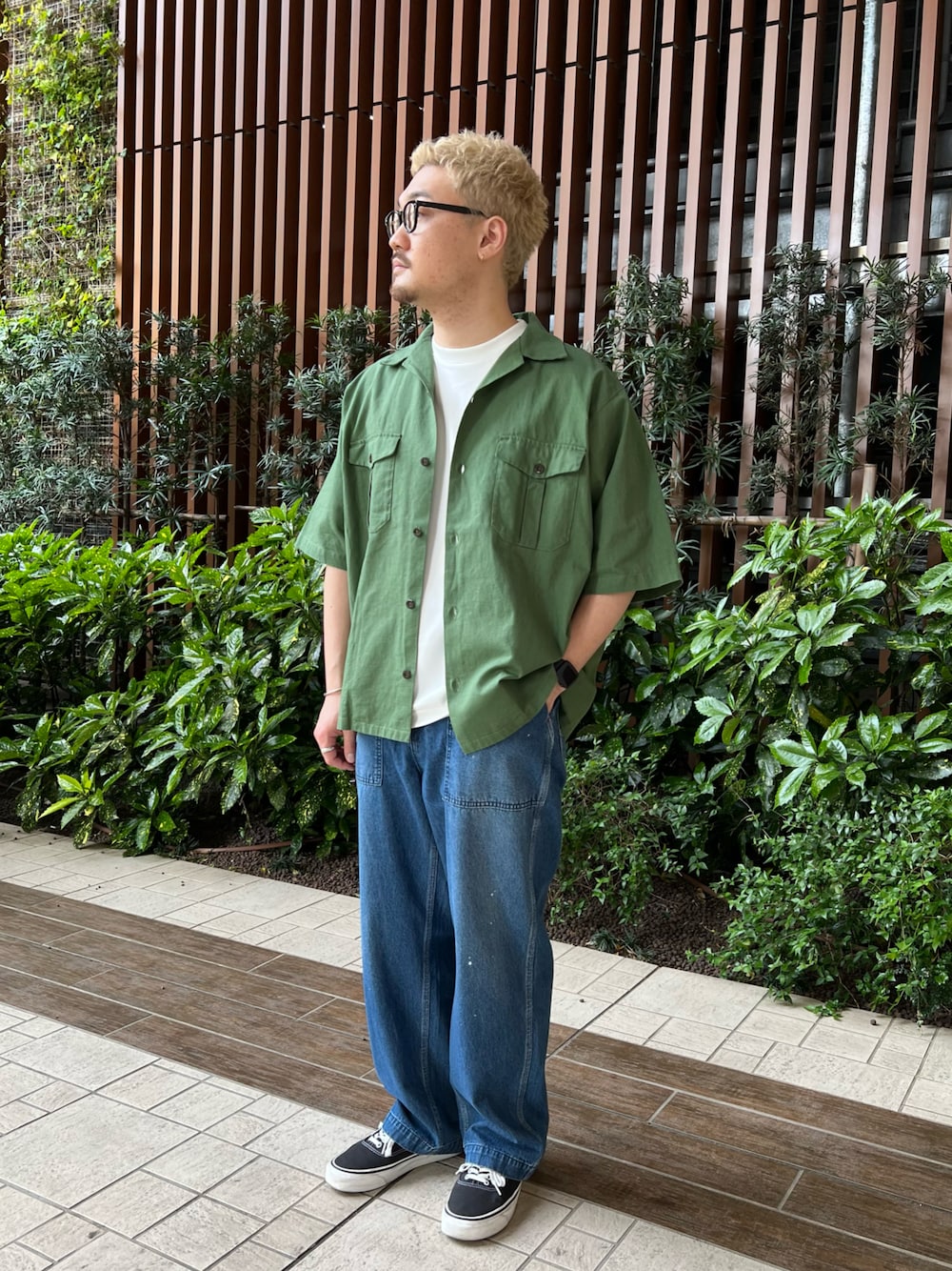 グリーン系のシャツ/ブラウス、ブラック系のスニーカー、ブルー系のデニムパンツを着用したメンズの春コーディネートの1枚目の写真