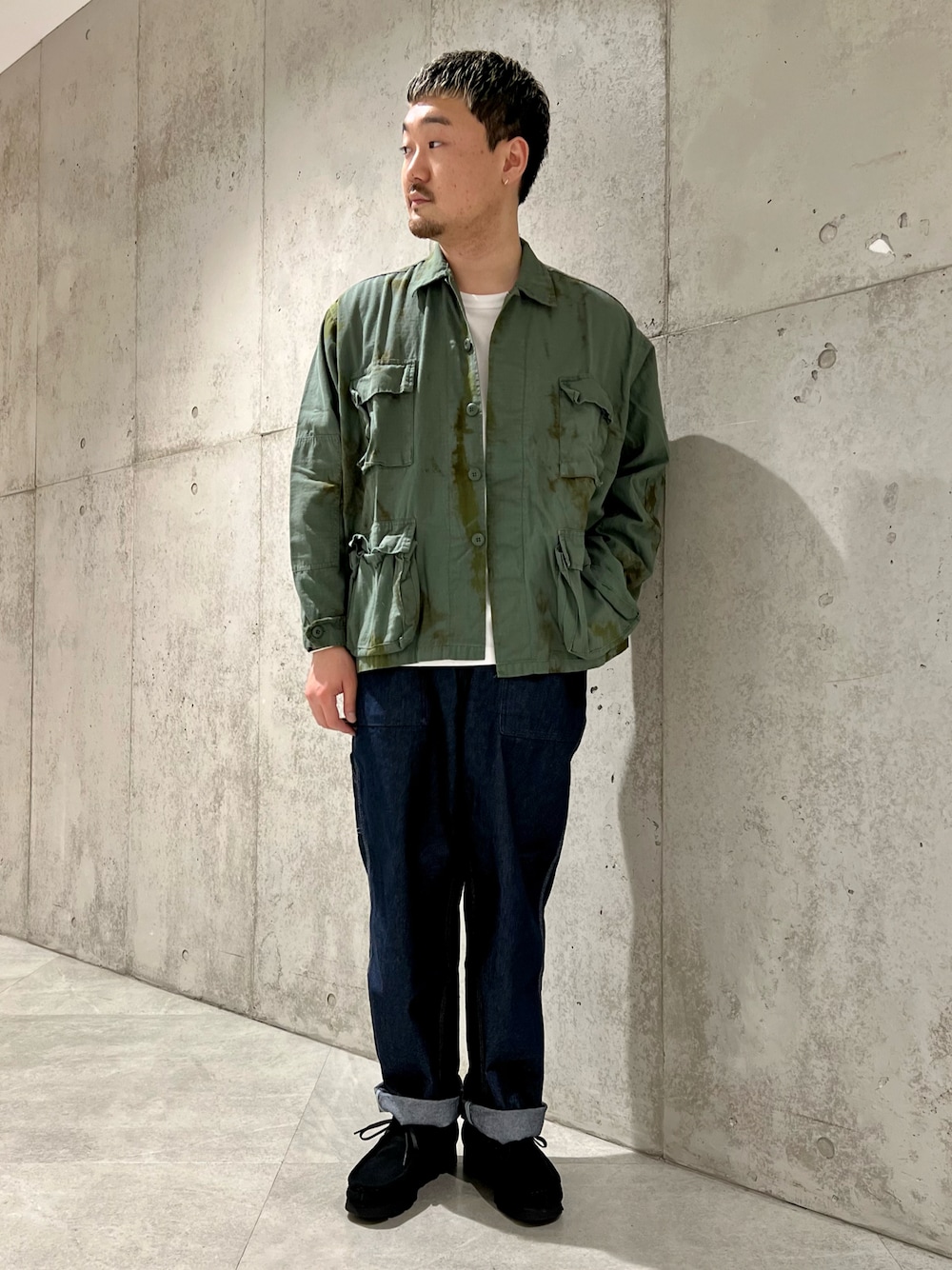 ブルー系のデニムパンツ、ブラック系のブーツ、ブルー系のミリタリージャケットを着用したメンズの春コーディネートの1枚目の写真