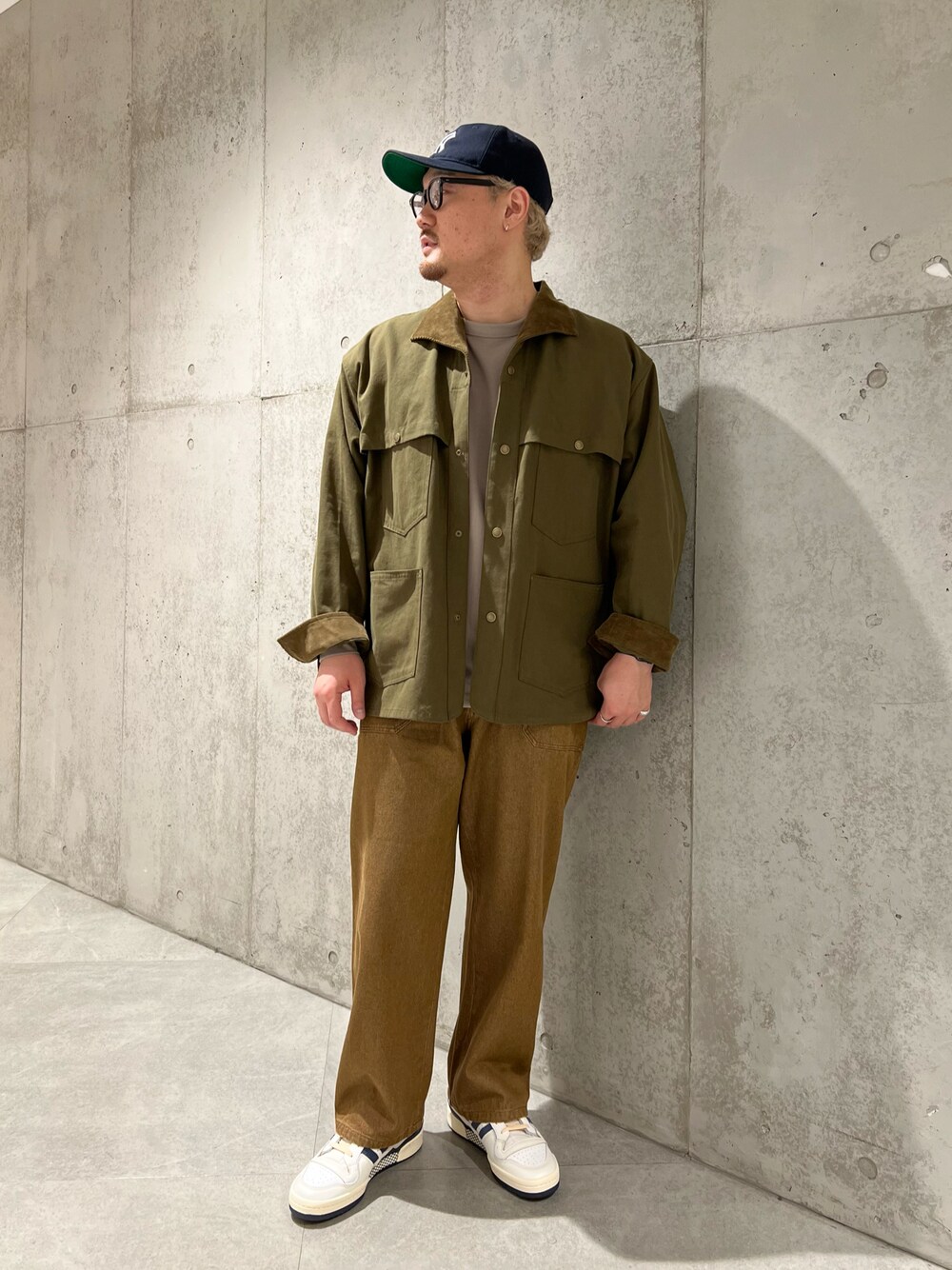 グリーン系のカバーオール、ベージュ系のTシャツ/カットソー、ブラウン系のデニムパンツを着用したメンズの秋コーディネートの1枚目の写真