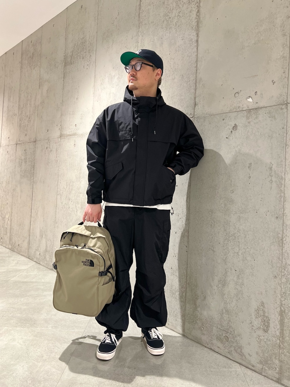 ホワイト系のTシャツ/カットソー、ベージュ系のバックパック/リュック、ブラック系のスニーカーを着用したメンズの春コーディネートの1枚目の写真