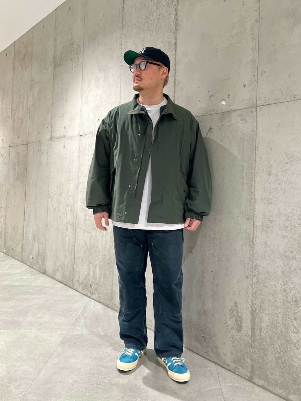 グリーン系のダウンジャケット/コート、ホワイト系のTシャツ/カットソー、ブルー系のスニーカーを着用したメンズの冬コーディネートの1枚目の写真