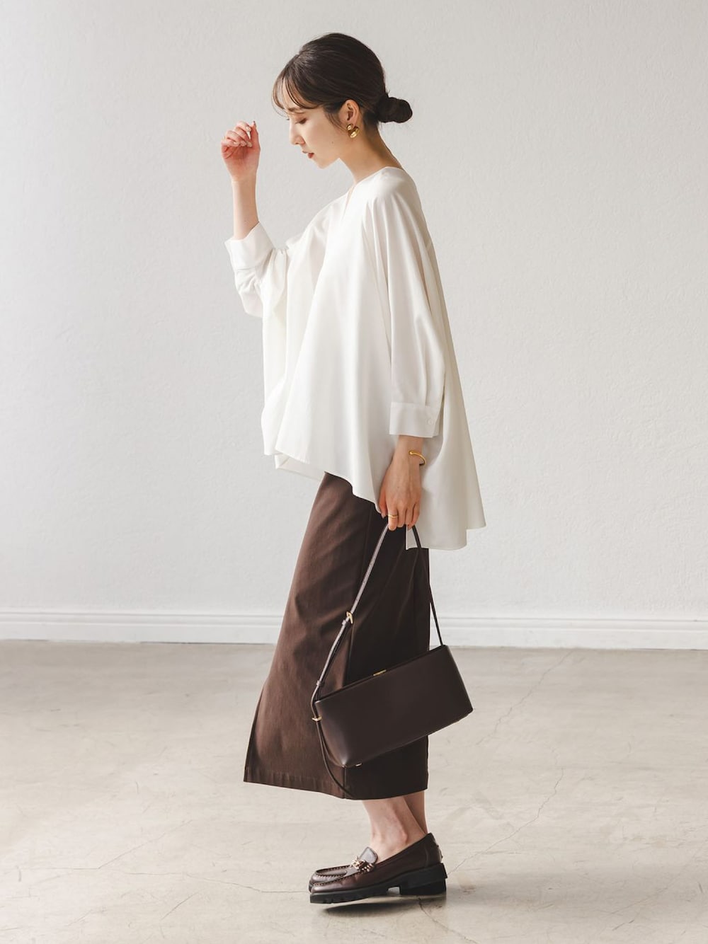 ホワイト系のシャツ/ブラウス、ブラウン系のスカート、ブラウン系のローファーを着用したレディースの秋コーディネートの1枚目の写真