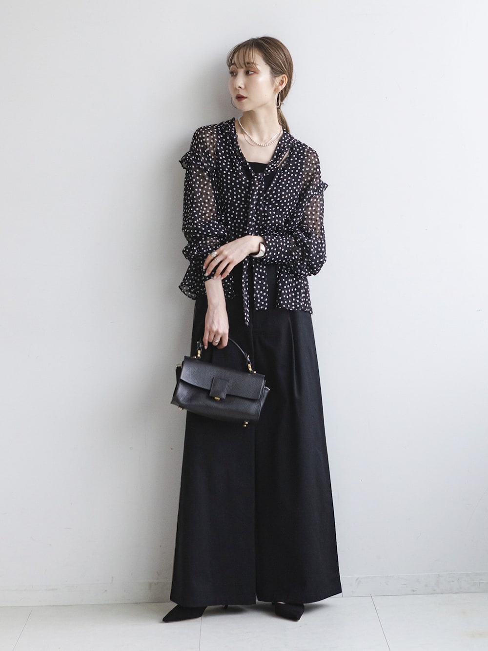 ブラック系のシャツ/ブラウス、ブラック系のスラックス、ブラック系のショルダーバッグを着用したレディースの秋コーディネートの1枚目の写真