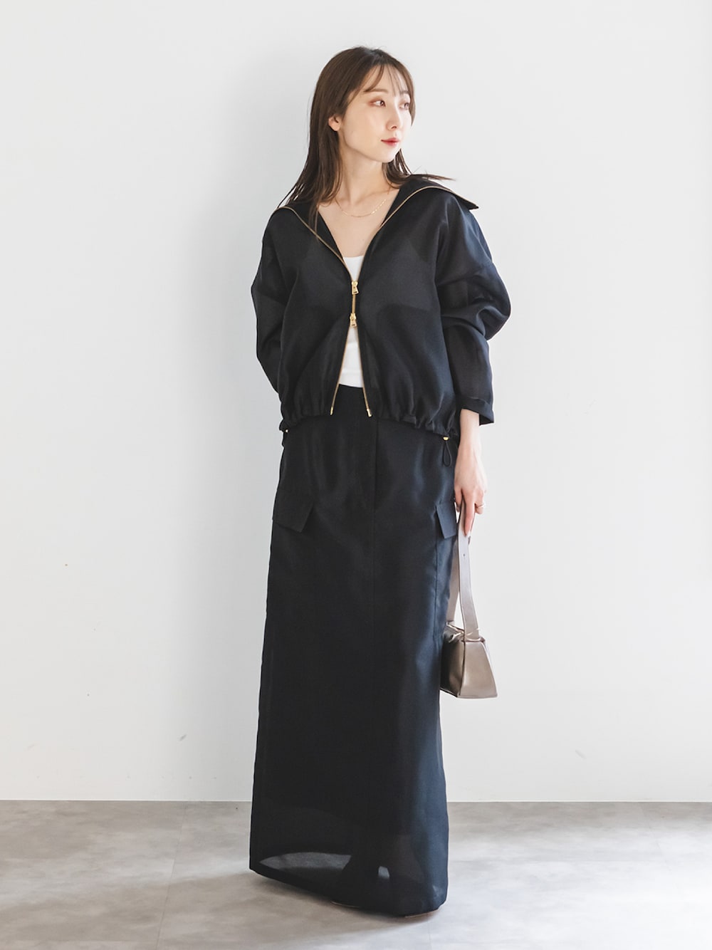 ブラック系のその他アウター、ブラック系のスカート、ブラウン系のショルダーバッグを着用したレディースの春コーディネートの1枚目の写真