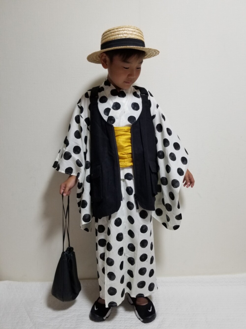 ブラック系のベスト、ブラック系のサンダル、ブラック系のハンドバッグを着用したキッズの夏コーディネートの1枚目の写真