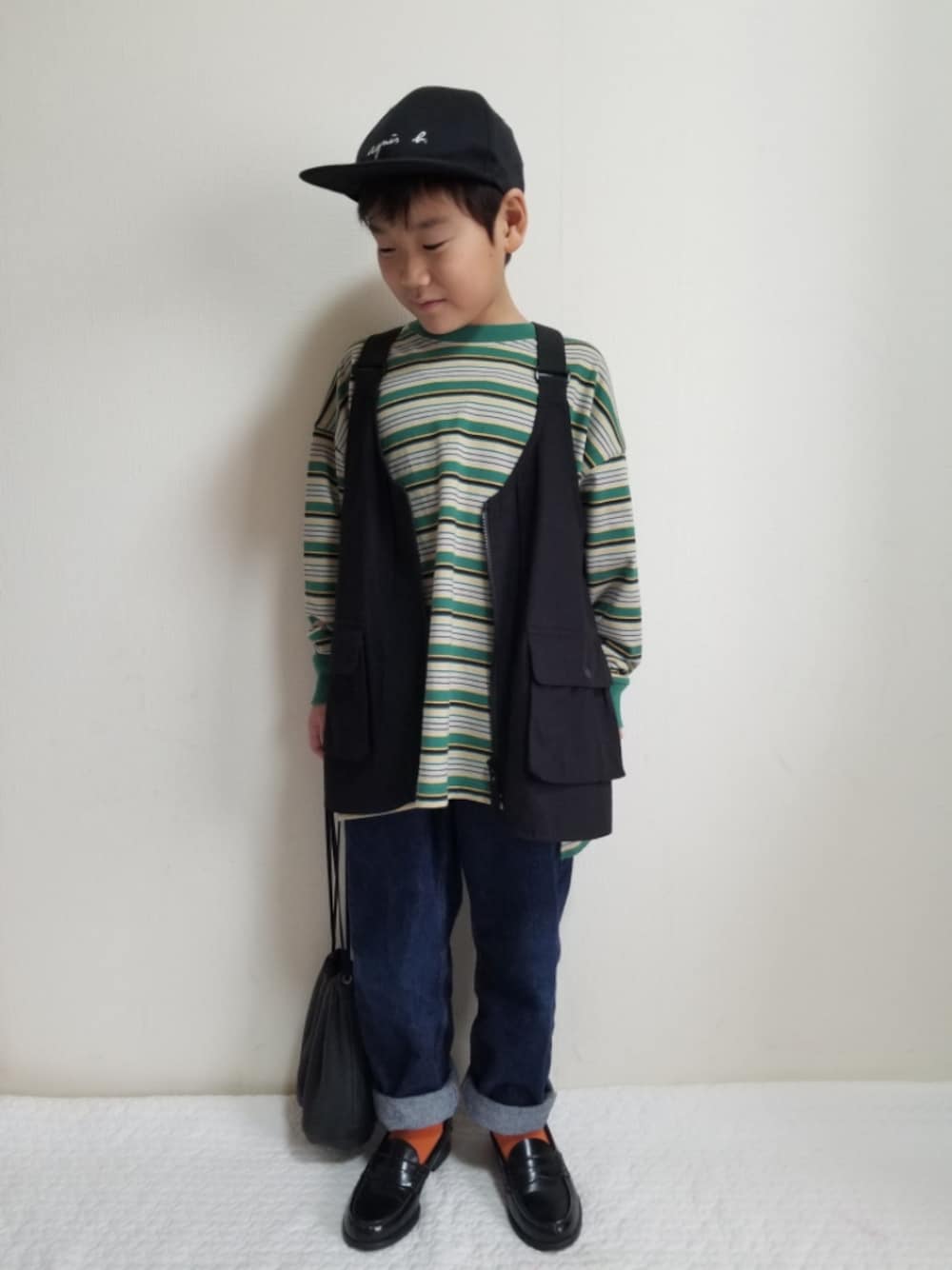 ブラック系のベスト、グリーン系のTシャツ/カットソー、ブルー系のデニムパンツを着用したキッズの秋コーディネートの1枚目の写真