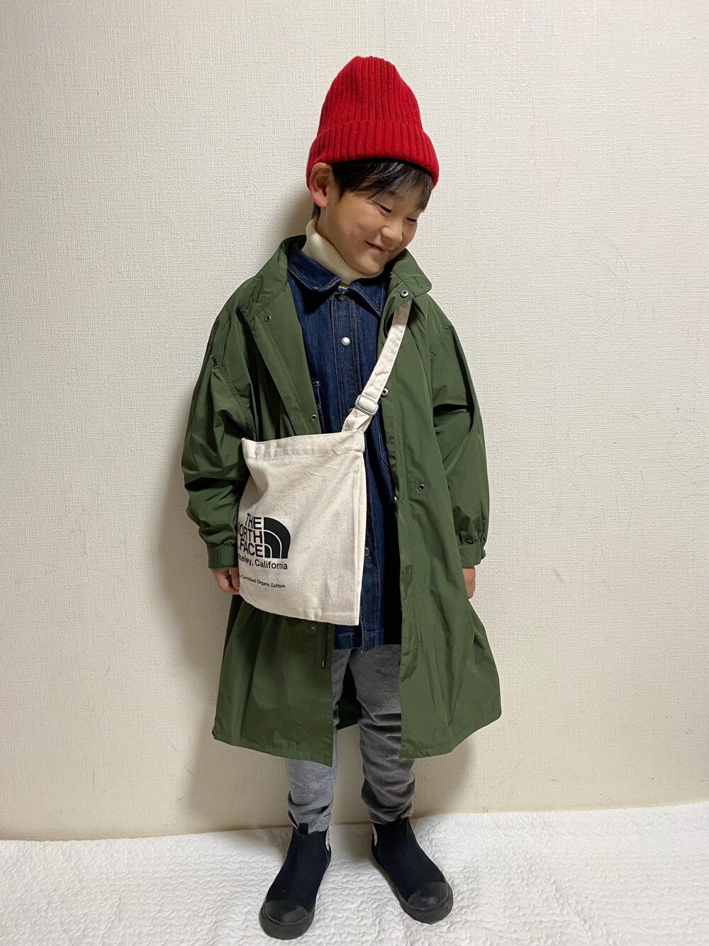 グリーン系のモッズコート、ブルー系のデニムジャケット、ホワイト系のニット/セーターを着用したキッズの冬コーディネートの1枚目の写真