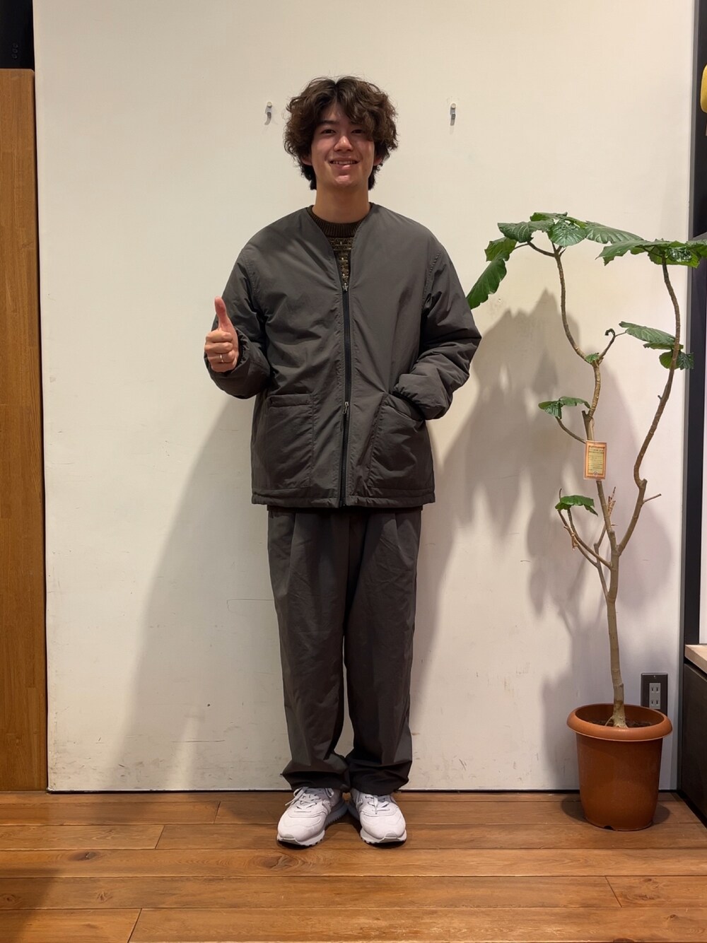 ブラウン系のニット/セーター、グレー系のダウンジャケット/コート、グレー系のその他パンツを着用したメンズの秋コーディネートの1枚目の写真