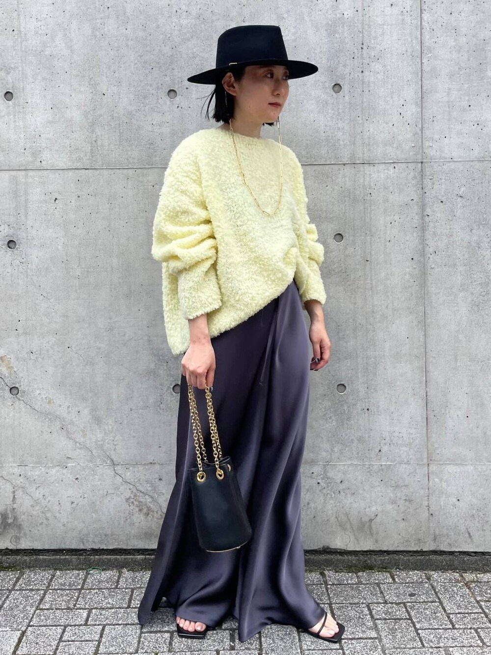 イエロー系のニット/セーター、グレー系のその他パンツを着用したレディースの夏コーディネートの1枚目の写真