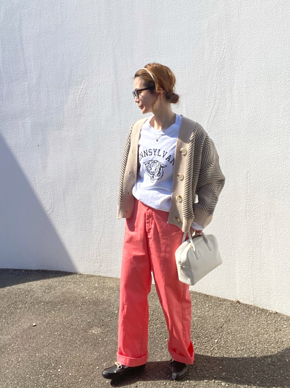 ホワイト系のTシャツ/カットソー、ブラック系のカーディガン/ボレロ、ピンク系のチノパンツを着用したレディースの春コーディネートの1枚目の写真