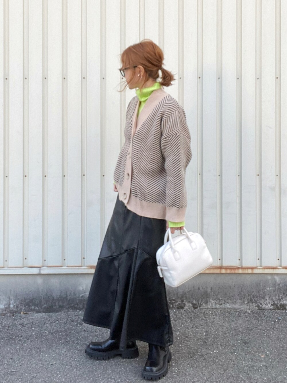 ブラック系のカーディガン/ボレロ、グリーン系のニット/セーター、ブラック系のスカートを着用したレディースの冬コーディネートの1枚目の写真