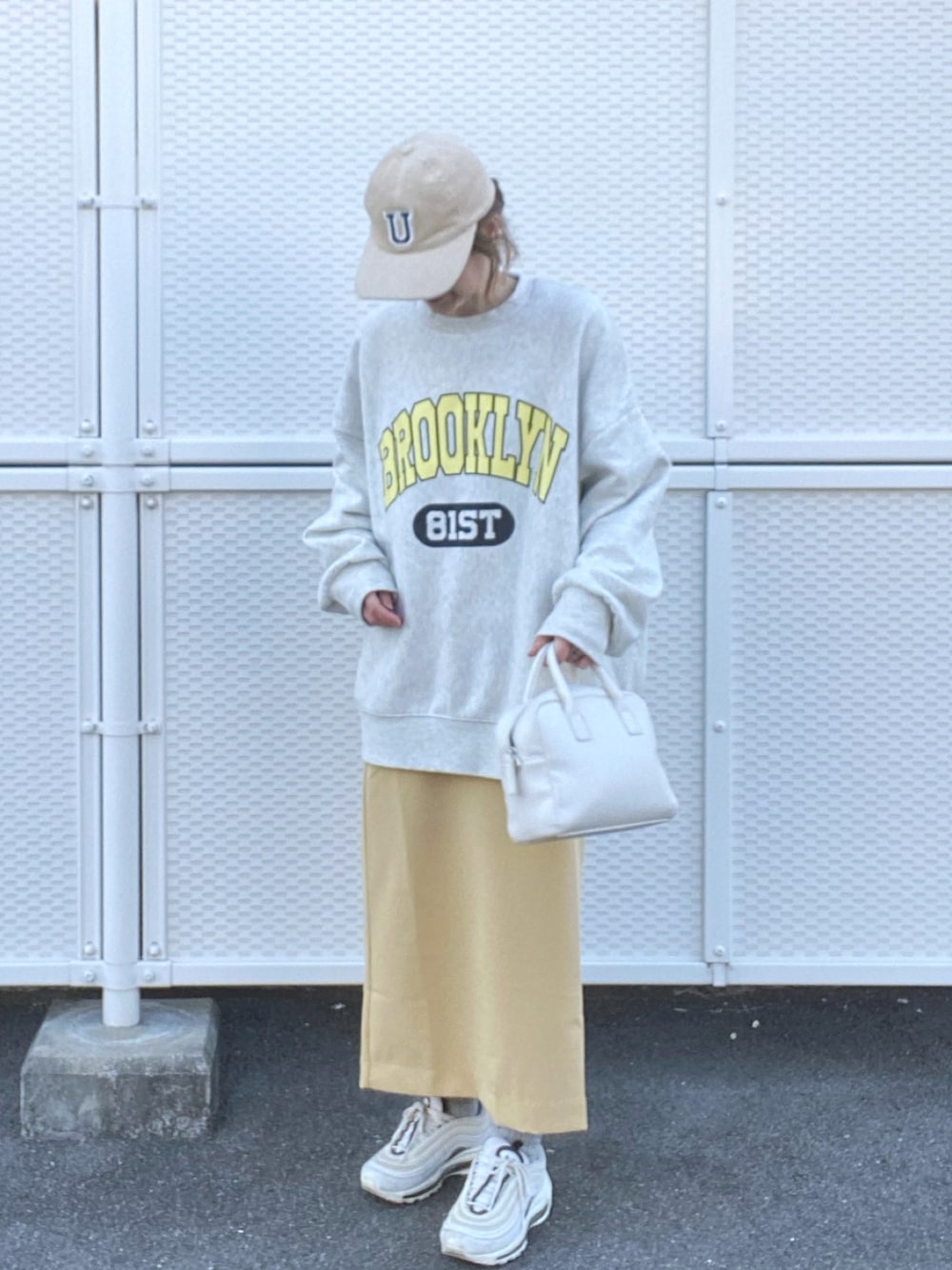 ベージュ系のスウェット、イエロー系のスカート、ホワイト系のボストンバッグを着用したレディースの冬コーディネートの1枚目の写真