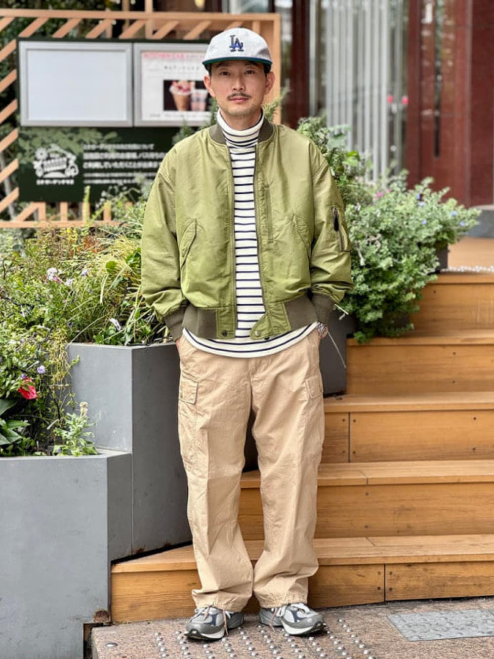グリーン系のブルゾン、ホワイト系のTシャツ/カットソー、ベージュ系のカーゴパンツを着用したメンズの秋コーディネートの1枚目の写真