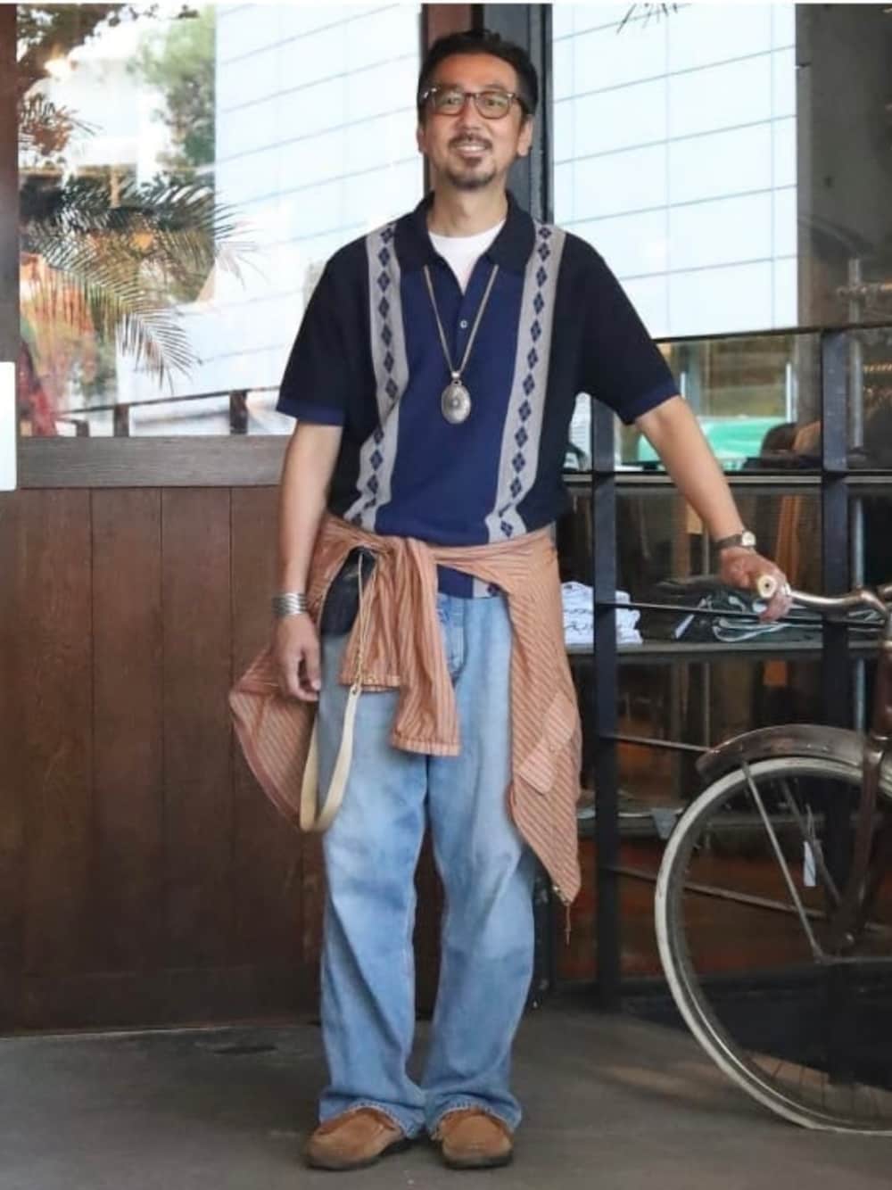 ブルー系のデニムパンツ、オレンジ系のブルゾン、ブルー系のポロシャツを着用したメンズの夏コーディネートの1枚目の写真