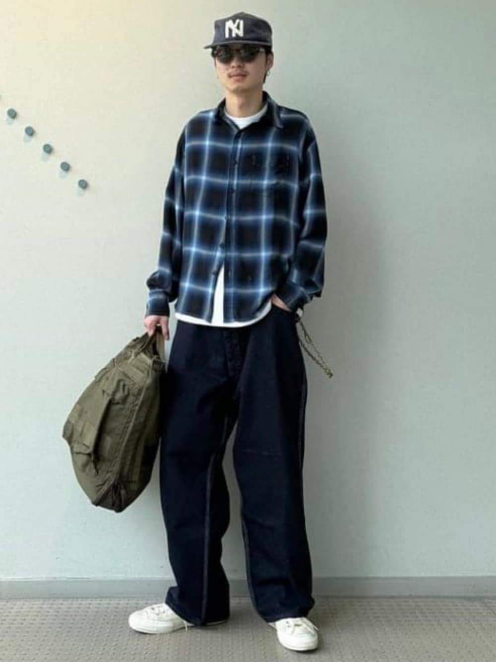 ブラック系のシャツ/ブラウス、グリーン系のトートバッグ、ブルー系のデニムパンツを着用したメンズの春コーディネートの1枚目の写真