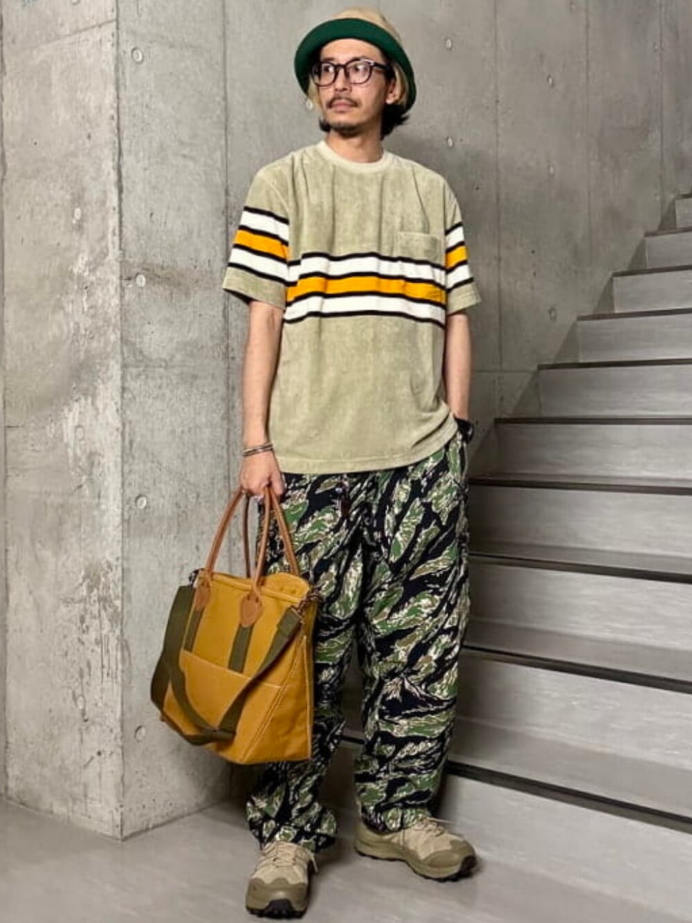 ブラウン系のトートバッグ、ベージュ系のTシャツ/カットソーを着用したメンズの夏コーディネートの1枚目の写真