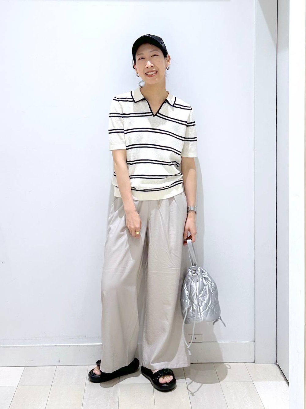 シルバー系のハンドバッグ、ベージュ系のその他パンツ、ホワイト系のニット/セーターを着用したレディースの春コーディネートの1枚目の写真