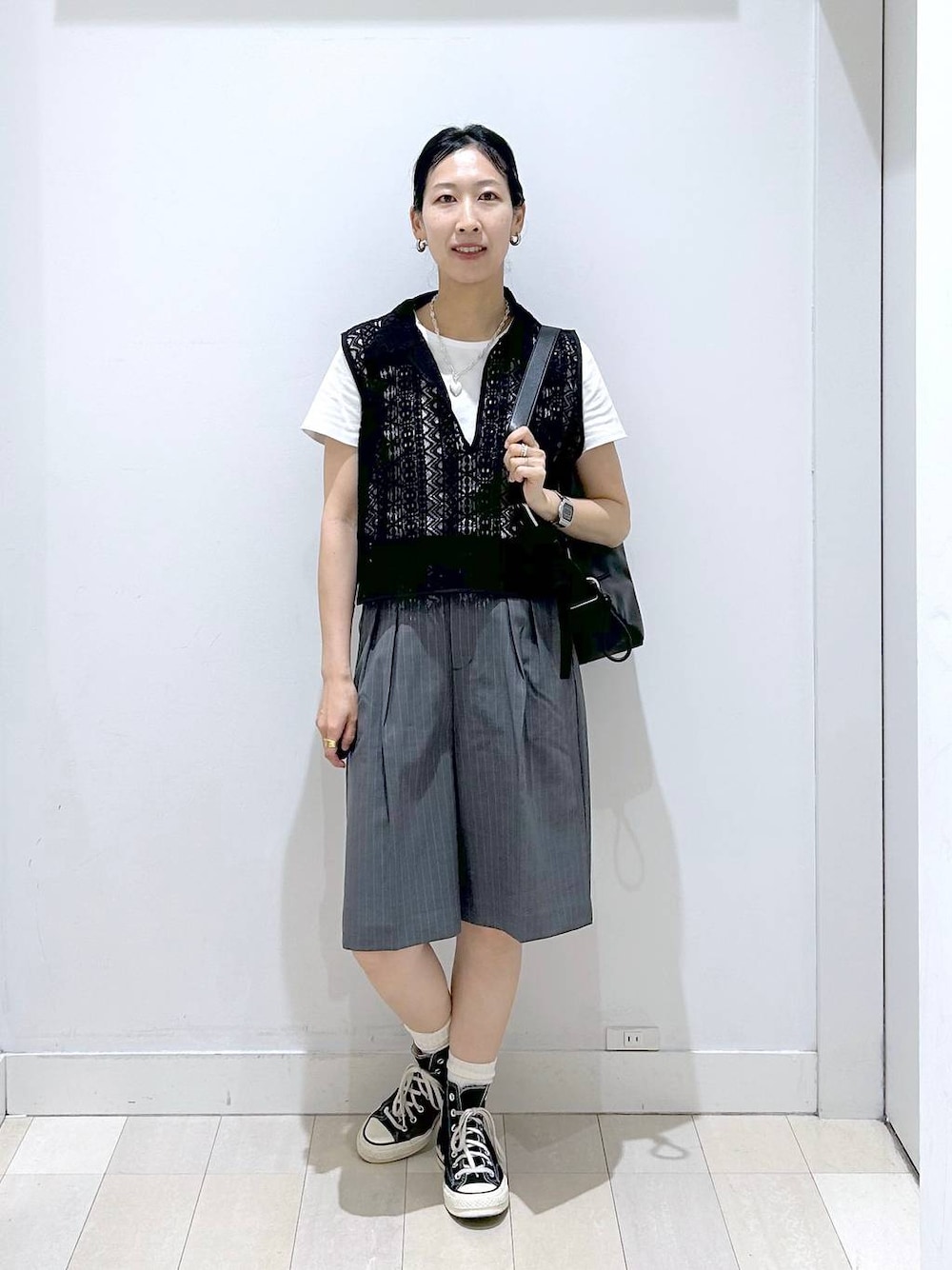 ブラック系のショルダーバッグ、ホワイト系のTシャツ/カットソー、ブラック系のベストを着用したレディースの夏コーディネートの1枚目の写真