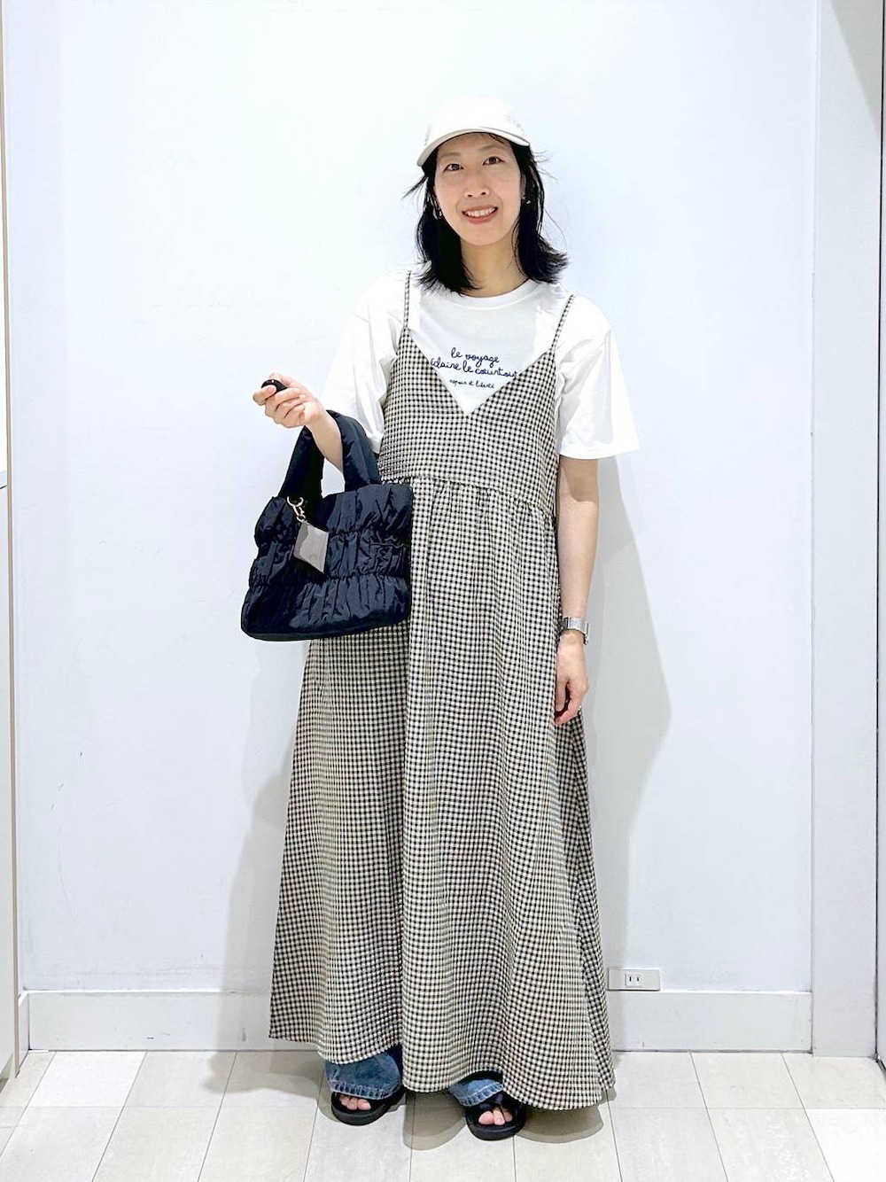 ブルー系のデニムパンツ、ブラック系のトートバッグ、ホワイト系のTシャツ/カットソーを着用したレディースの夏コーディネートの1枚目の写真