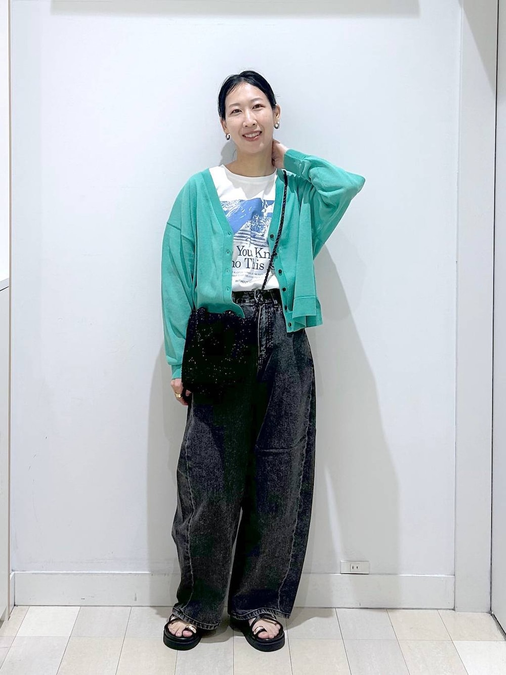 ブラック系のデニムパンツ、ホワイト系のTシャツ/カットソー、グリーン系のカーディガン/ボレロを着用したレディースの春コーディネートの1枚目の写真