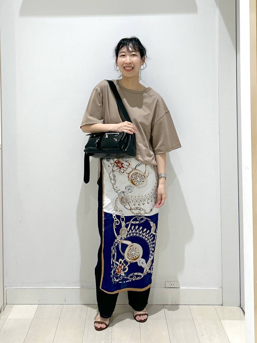 ブルー系のデニムパンツ、ブラック系のショルダーバッグ、ベージュ系のTシャツ/カットソーを着用したレディースの夏コーディネートの1枚目の写真