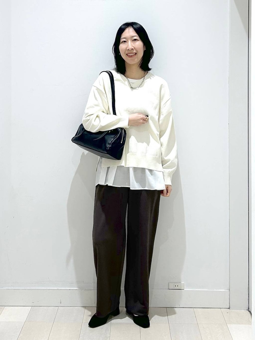 ベージュ系のニット/セーター、ブラウン系のその他パンツ、ホワイト系のタンクトップを着用したレディースの春コーディネートの1枚目の写真