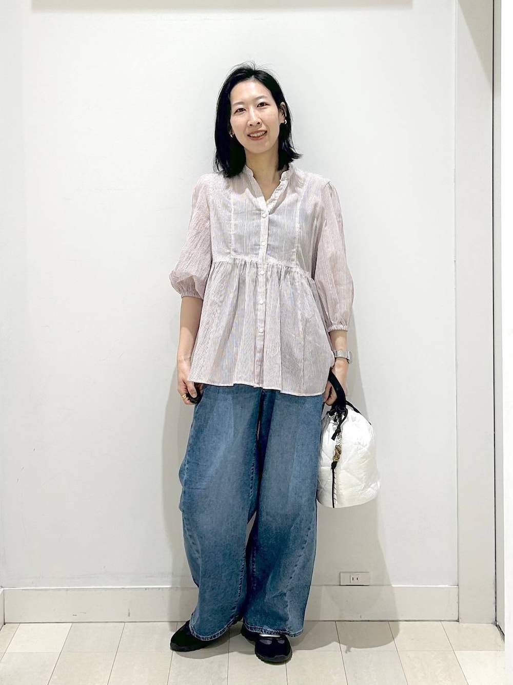 ホワイト系のハンドバッグ、ブルー系のデニムパンツ、レッド系のシャツ/ブラウスを着用したレディースの春コーディネートの1枚目の写真