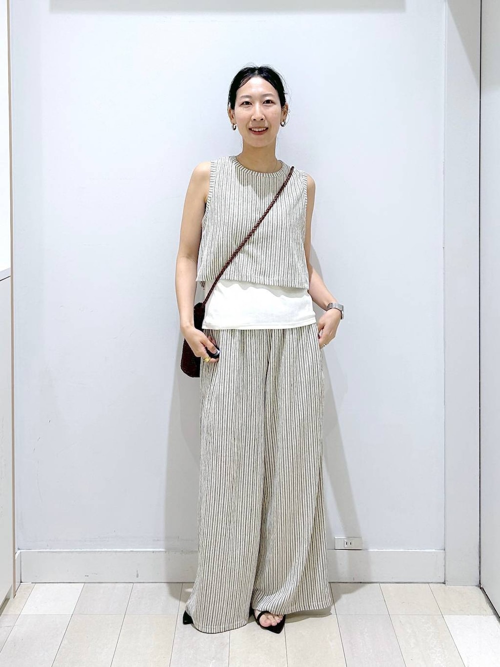 ブラウン系のクラッチバッグ、ホワイト系のその他パンツ、ホワイト系のTシャツ/カットソーを着用したレディースの夏コーディネートの1枚目の写真