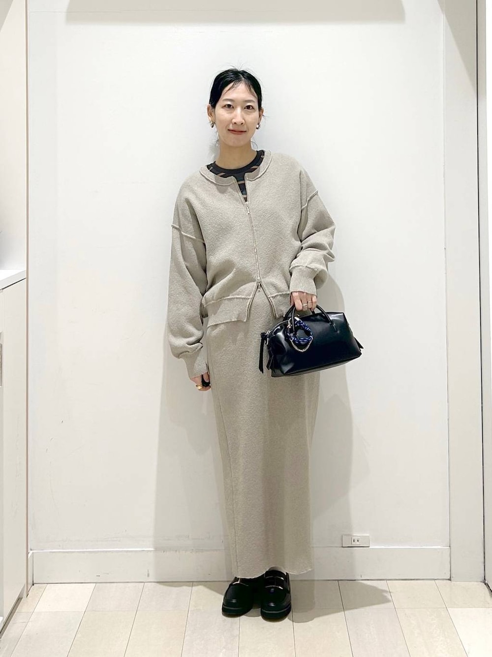 ブラック系のローファー、ベージュ系のワンピース、グレー系のTシャツ/カットソーを着用したレディースの春コーディネートの1枚目の写真